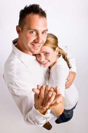 Couple hugging and displaying engagement ring