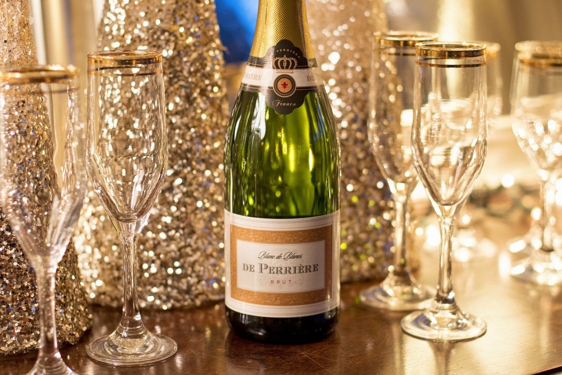 Bottle of champagne with champagne flutes and glitter covered bottles