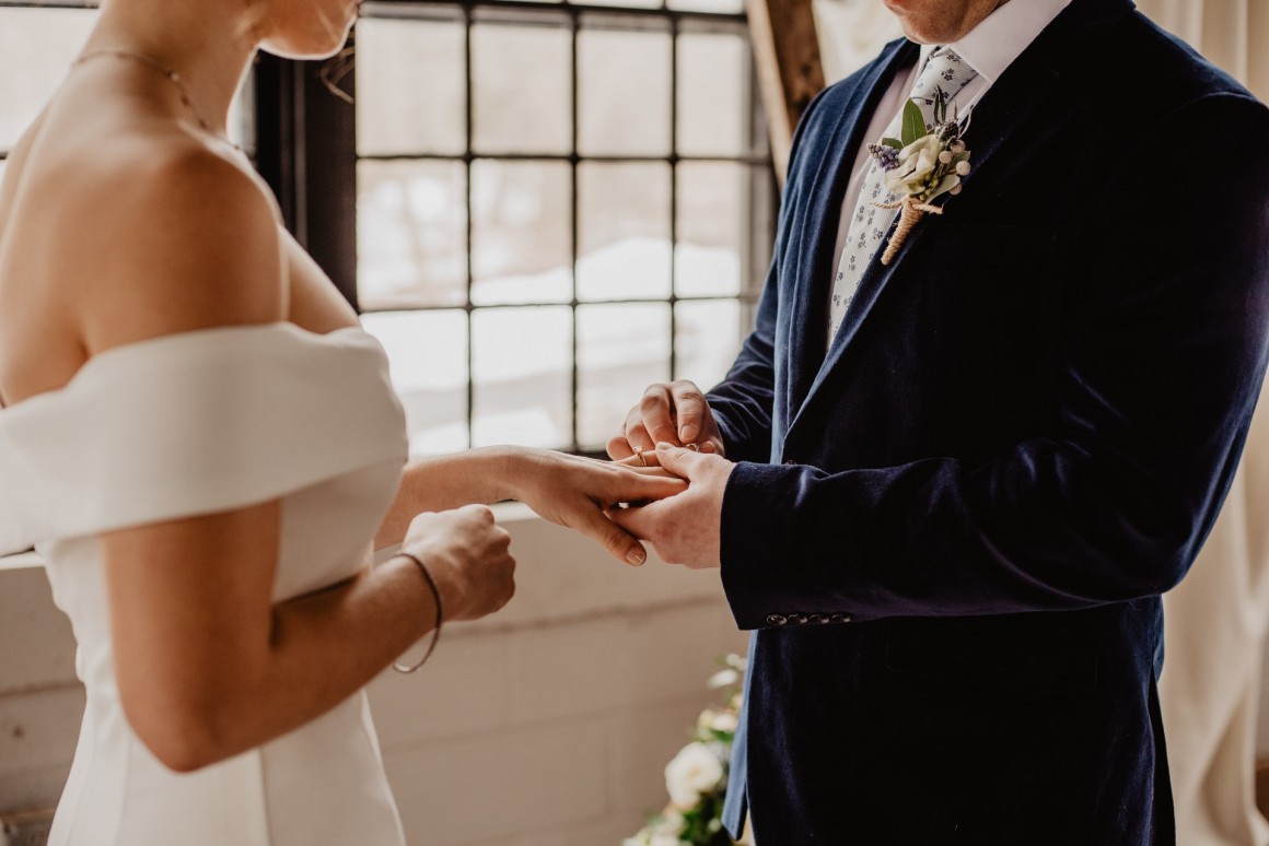 Groom placing ring on brides finger at wedding ceremony