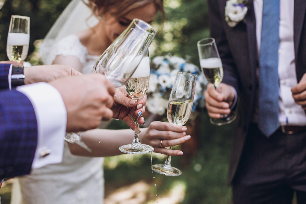 Bride and groom clicking champagne glasses during wedding toast