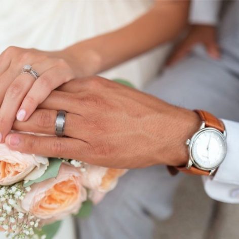 Picture of Bride and Groom Hands Intertwined with Wedding Bands Featured