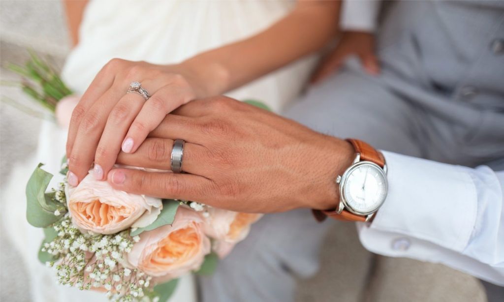 Picture of Bride and Groom Hands Intertwined with Wedding Bands Featured