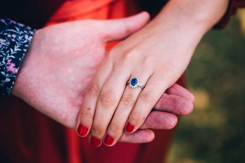 woman wearing sapphire ring holding hands