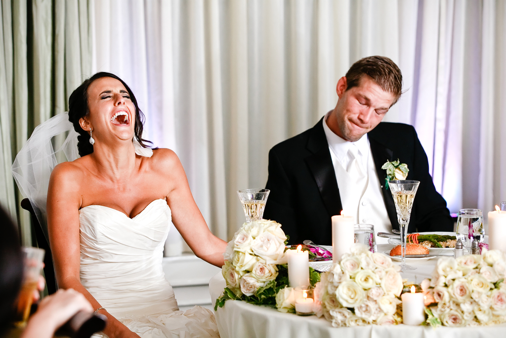 Bride laughing hilariously at wedding speech