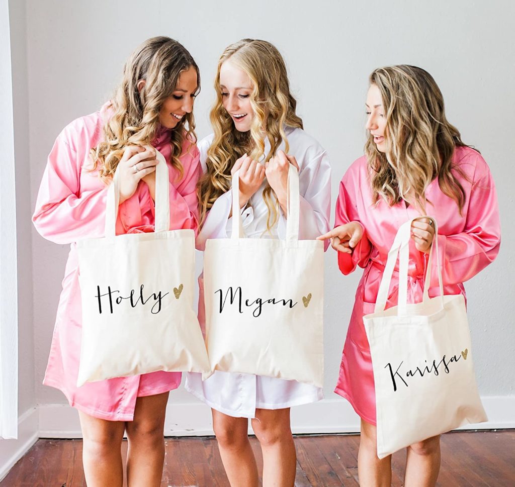 bride and bridesmaids wearing satin robes holding personalized canvas tote bags