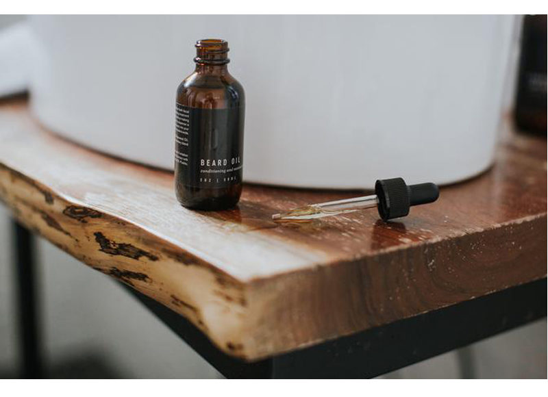 Natural beard oil bottle and dropper on wooden table