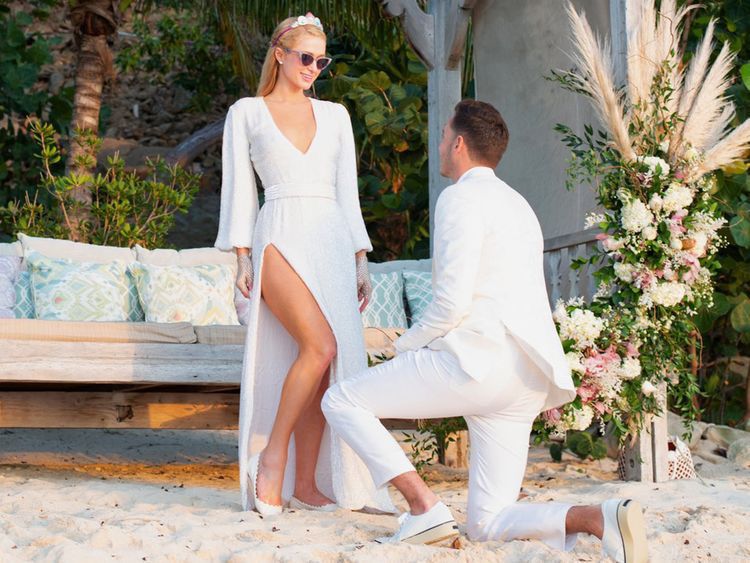 Paris Hilton posing on beach while Carter Reum is on one knee proposing