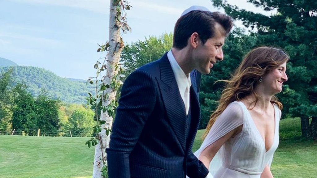Beautiful bride Grace Gummer holding her new husband Mark Ronson's hand in field.