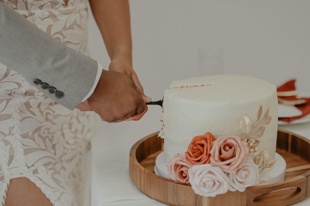 Bride and Groom cut small cake with blush, white, and orange flowers