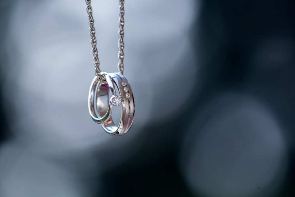 two silver wedding bands hanging from silver chain