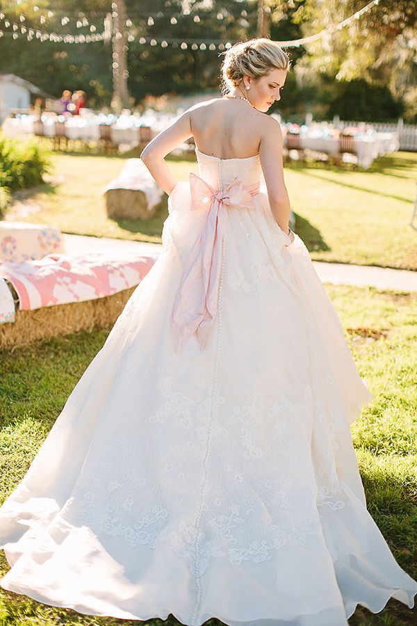 Bride at outdoor wedding wearing ballgown with oversized pink bow