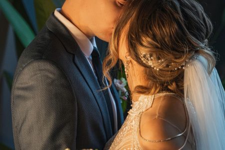 Bride in customized wedding dress kissing groom during ceremony