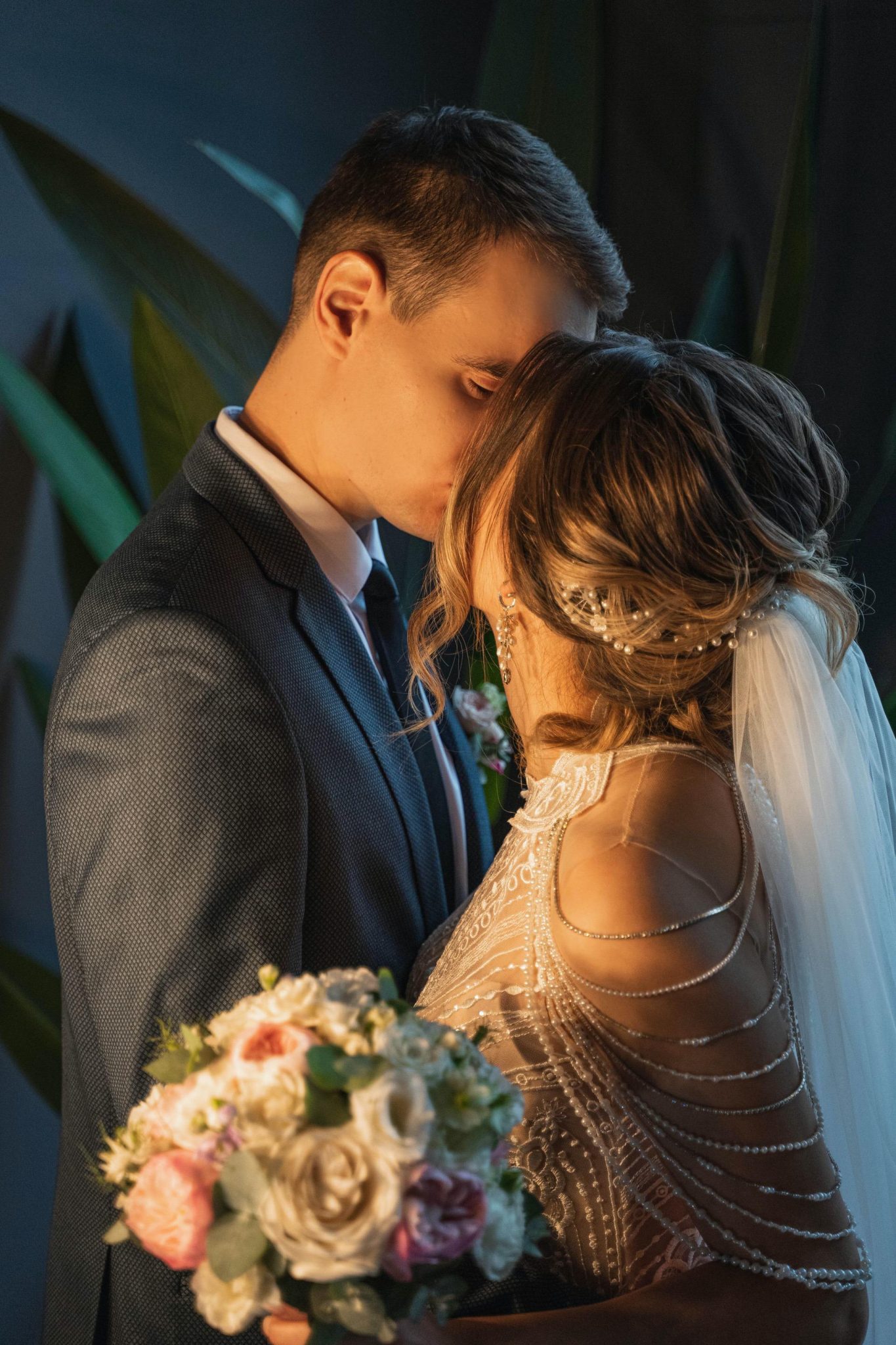 Bride in customized wedding dress kissing groom during ceremony