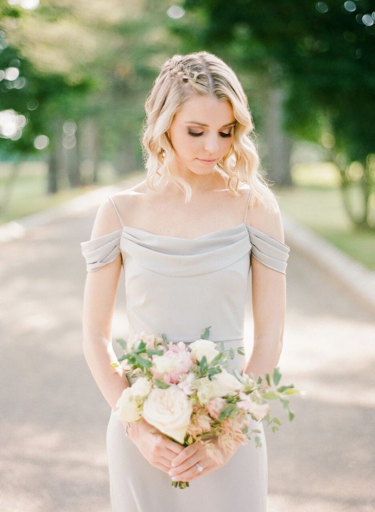 Bridesmaid wearing taupe off the shoulder dress and french braid hairstyle