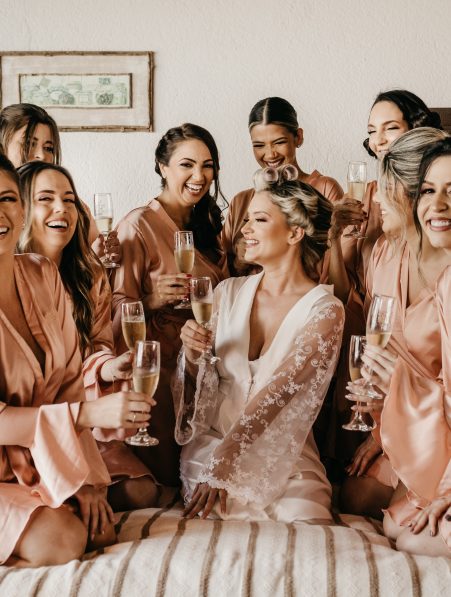 bride and bridesmaid taking a photo while holding champagne glasses