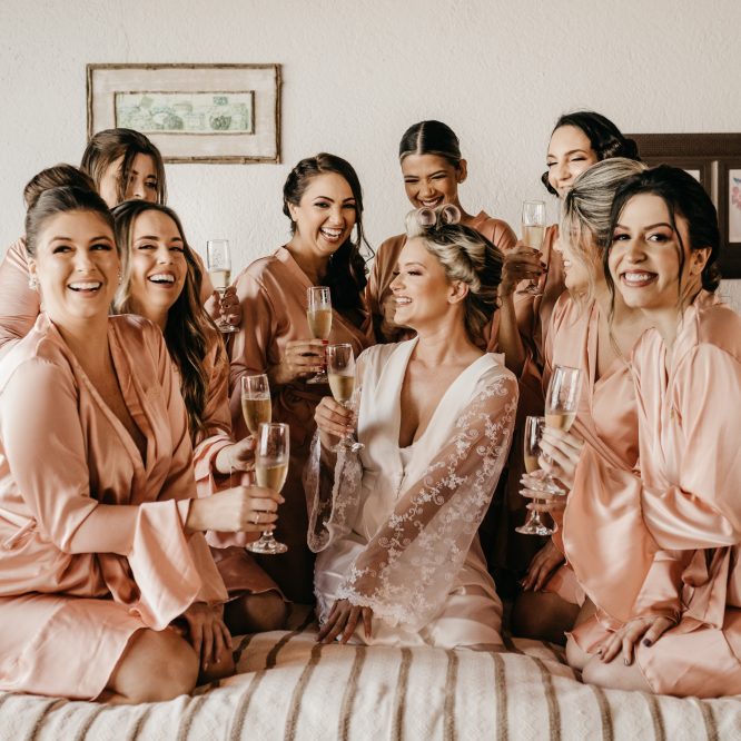 bride and bridesmaid taking a photo while holding champagne glasses
