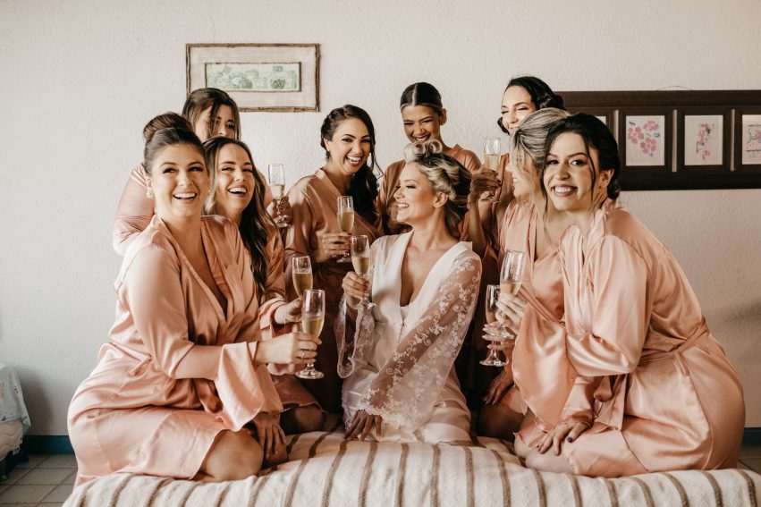 bride and bridesmaid taking a photo while holding champagne glasses