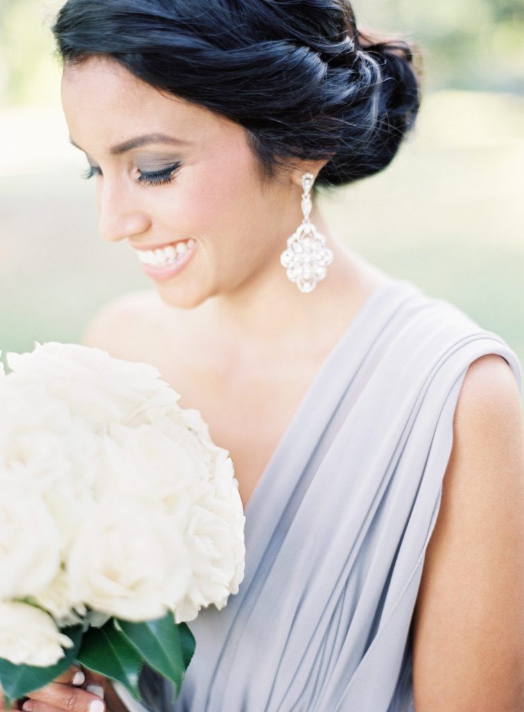 beautiful bridesmaid wearing one shoulder lilac dress holding bouquet with ivory flowers.