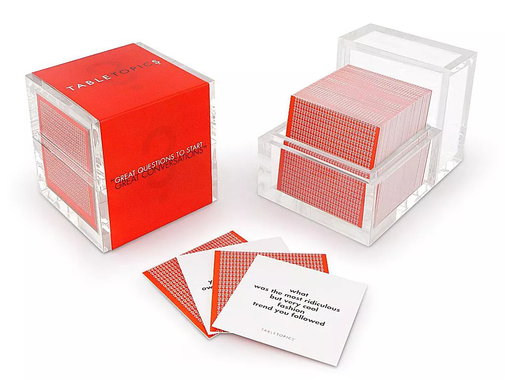A pack of TableTopics conversation cards, with the top card reading "what was the most ridiculous but very cool fashion trend you followed"