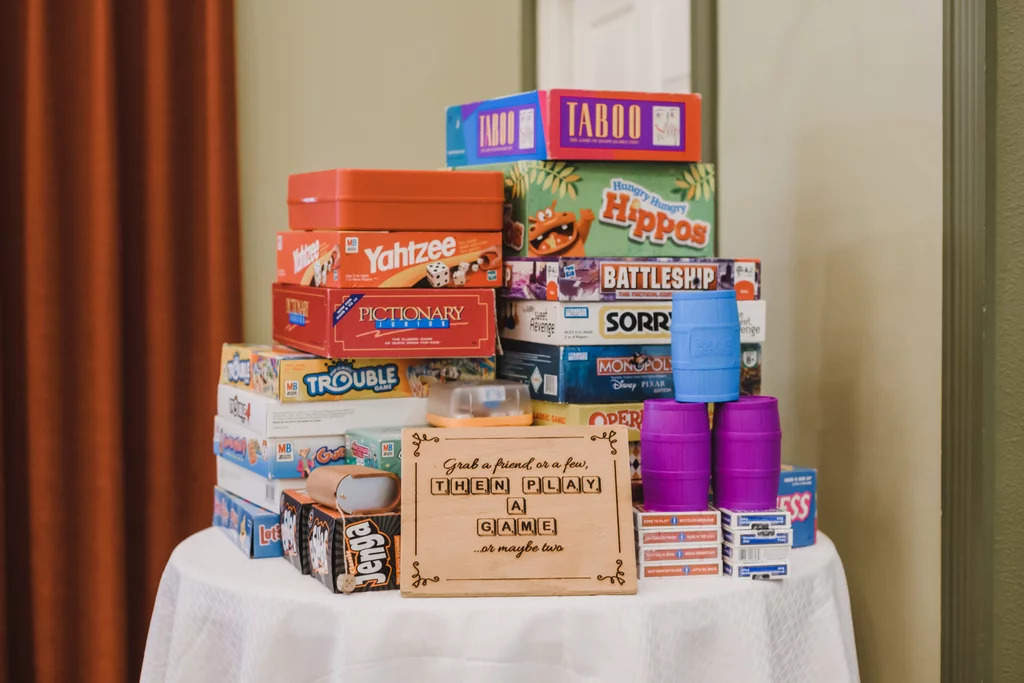 An assortment of board games with a sign inviting guests to play